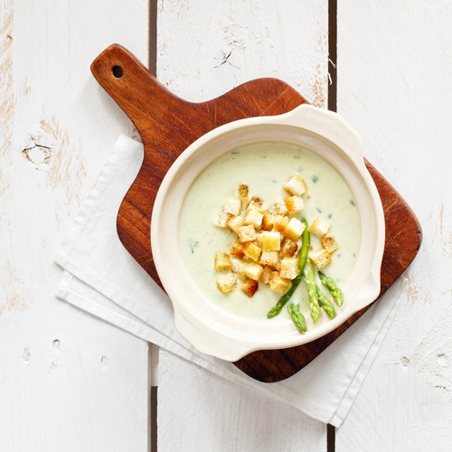 Aspergesoep met croutons in kommetje op houten plank