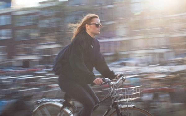 Meisje met zonnebril fietst door stad